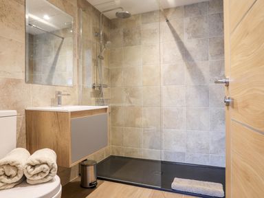 A bathroom with a walk-in shower sink with mirror and toilet with towels at The Herun in Rhosneigr