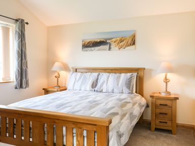 A bedroom with a wooden bed and two bedside tables with lamps at The Herun in Rhosneigr