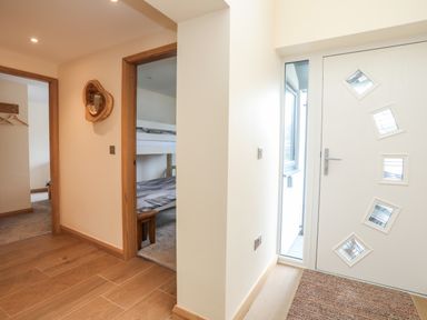 A hallway with wooden floor and a white front door with diamond windows at The Herun in Rhosneigr