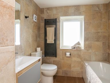 A bathroom with a toilet sink bathtub window and towel rack at The Herun in Rhosneigr