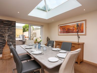 A dining room with a table set and chairs under a skylight at The Herun in Rhosneigr