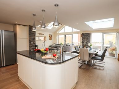 A kitchen with an island countertop and dining area with chairs at The Herun in Rhosneigr
