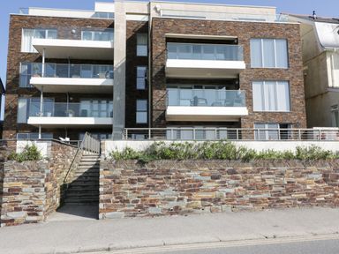 The exterior of a three story building with balconies and stone walls at Newquay Fistral Beach View in Newquay