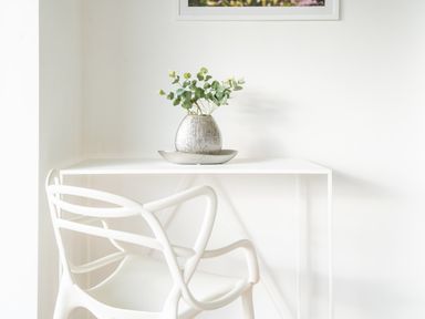 A white desk with a decorative silver vase holding green foliage and a modern white chair at Newquay Fistral Beach View in Newquay