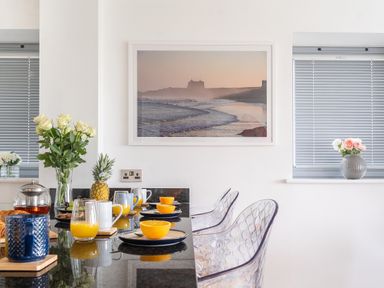 A kitchen countertop with glasses of orange juice mugs plates with oranges flowers and a pineapple in Newquay Fistral Beach View in Newquay