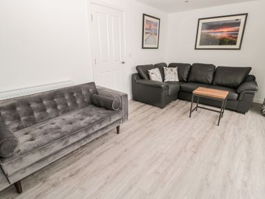 A living room with two sofas a wooden table and framed pictures on the wall at Amble Views in Amble
