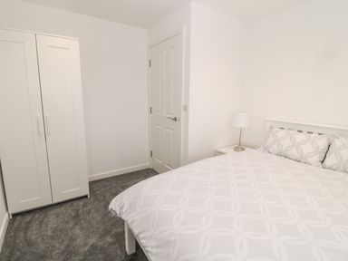 A bedroom with a bed pillow lamp wardrobe and door at Amble Views in Amble