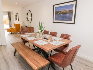 A dining area with wooden table brown chairs bench and wall art at Amble Views in Amble
