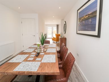 A dining room with a wooden table and six brown chairs at Amble Views in Amble