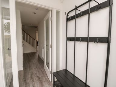 An entryway with a black coat rack and bench a hallway with a staircase at Amble Views in Amble
