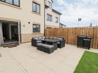 A backyard patio with outdoor seating and a barbecue grill at Amble Views in Amble