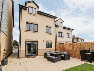 A backyard patio with outdoor seating and a barbecue grill at Amble Views in Amble