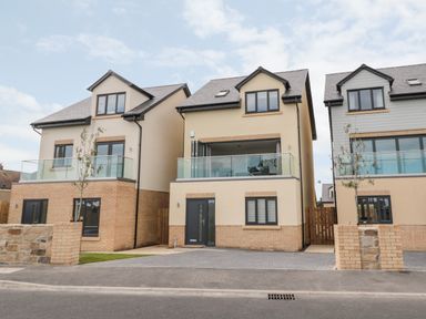 Three modern detached houses with balconies and driveways at Amble Views in Amble