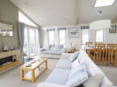 A living room with sofas coffee table dining table and paintings at 44 Heritage Park in Stepaside near Kilgetty