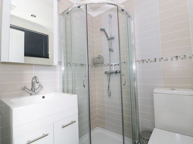 A bathroom with a shower cubicle sink with faucet mirror and toilet at 44 Heritage Park Stepaside near Kilgetty