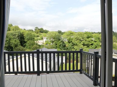 A balcony with black railings overlooking white buildings and trees at 44 Heritage Park in Stepaside near Kilgetty