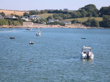 A coastal scene with boats on water and houses with trees on a hillside at Little Starboard in Kingsbridge