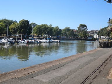 A river with boats docked along the side and a paved pathway beside it at Little Starboard in Kingsbridge