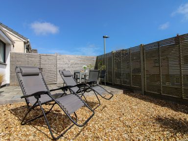 A garden with deck chairs and a table at Little Starboard in Kingsbridge
