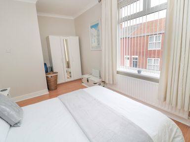 A bedroom with a bed pillow wardrobe window with blinds and curtains at Sandy Toes Cottage in Newbiggin-By-The-Sea