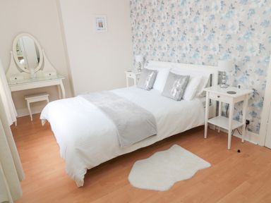 A bedroom with a double bed and floral wallpaper at Sandy Toes Cottage in Newbiggin-By-The-Sea