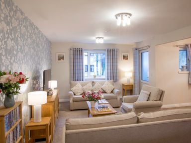 A living room with sofas a coffee table a television and lamps at Honeybee Cottage in Berrier near Penruddock