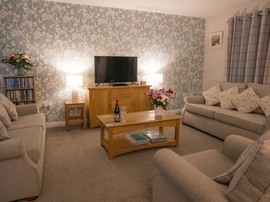 A living room with two sofas an armchair wooden coffee table and a TV on a cabinet at Honeybee Cottage in Berrier near Penruddock