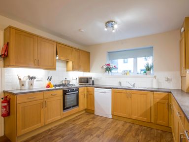 A kitchen with wooden cabinets appliances and a window at Honeybee Cottage in Berrier near Penruddock