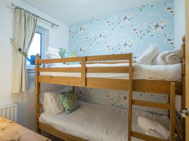 A small bedroom with wooden bunk beds and animal print wallpaper at Honeybee Cottage in Berrier near Penruddock