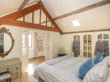 A bedroom with a bed pillows robes hanging on closet doors and a vanity table with mirror at The Coach House Merrion near Pembroke
