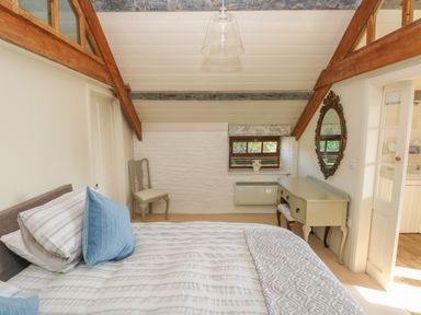A bedroom with a bed pillows a chair a dressing table and mirror at The Coach House Merrion near Pembroke