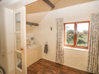 A bathroom with a sink unit and a window with curtains at The Coach House Merrion near Pembroke