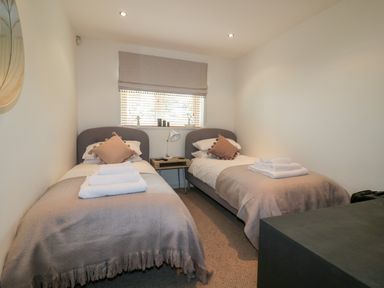 A bedroom with two single beds with beige blankets and brown pillows at The Bolt Hole in Downderry