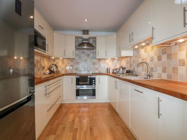 A kitchen with wooden countertops stainless steel appliances and tiled backsplash at The Bolt Hole in Downderry
