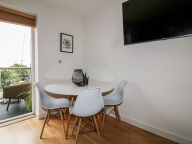 A dining area with a round table and four chairs near a sliding door leading to an outdoor space at The Bolt Hole in Downderry