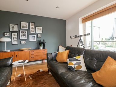 A living room with leather sofas cushions telescope and picture frames on the wall at The Bolt Hole in Downderry