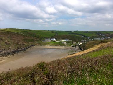 A coastal bay with a sandy beach surrounded by green hills and houses at Y Twll Bollt The Bolt Hole in Folkeston Hill Nolton Haven West Wales Pembrokeshire