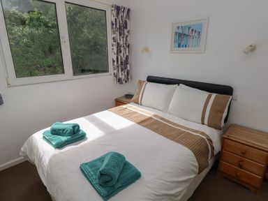 A bedroom with a double bed next to two wooden bedside tables at Y Twll Bollt in Folkeston Hill Nolton Haven West Wales & Pembrokeshire