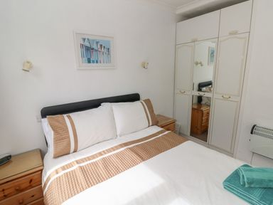A bedroom with a bed, bedside tables, wall lights, and a wardrobe with mirrored doors at Y Twll Bollt The Bolt Hole in Folkeston Hill Nolton Haven West Wales and Pembrokeshire