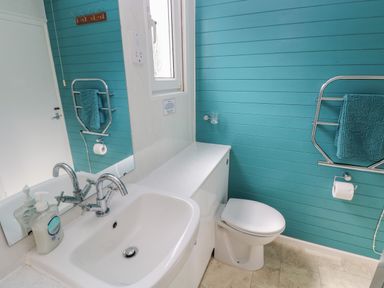 A bathroom with a sink soap dispenser a toilet and towels on racks at Y Twll Bollt The Bolt Hole in Folkeston Hill Nolton Haven West Wales and Pembrokeshire