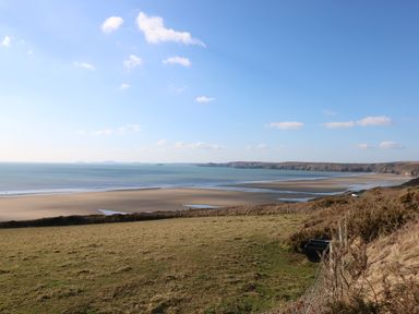 A coastal landscape with a sandy beach and grassy fields at Y Twll Bollt at Folkeston Hill Nolton Haven West Wales and Pembrokeshire