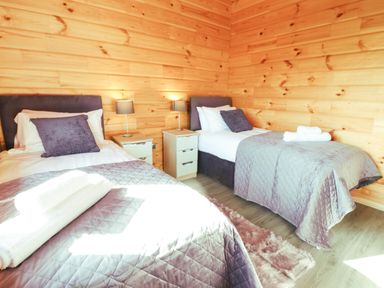A bedroom with two single beds bedside tables and lamps at Bacheiddon Log Cabin in Aberhosan near Machynlleth