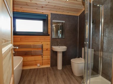 A bathroom with a bathtub toilet sink shower and towel rack at Bacheiddon Log Cabin Aberhosan near Machynlleth