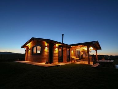 A log cabin with outdoor seating and lighting at dusk at Bacheiddon Log Cabin Aberhosan near Machynlleth