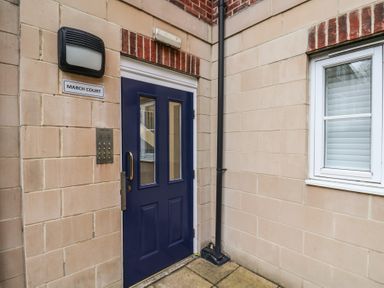 An exterior entrance with a blue door a window a doorbell panel a light and a sign saying March Court