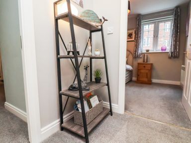 A shelving unit with decorative items and books in a hallway near a bedroom at Esk Retreat in Whitby