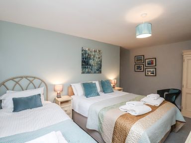 A bedroom with a double bed and a single bed with pillows and towels at Esk Retreat in Whitby