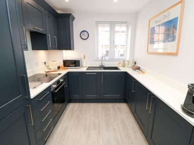 A kitchen with dark cabinets and white countertops a microwave sink and coffee machine at Esk Retreat in Whitby