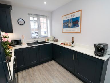 A kitchen with black cabinets white countertops a window microwave coffee machine and framed artwork at Esk Retreat in Whitby