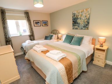 A bedroom with a double bed and a single bed with folded towels on them at Esk Retreat in Whitby